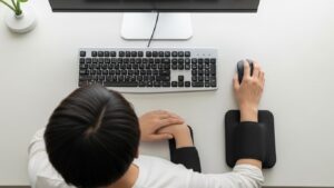 Mouse reach zone example showing mouse placed close to keyboard with elbow near the body while armrests support forearms without shoulder shrugging
