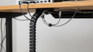Under-desk data cable spine with a small service loop near a docking station so cables stay tidy but can be unplugged and swapped easily